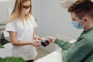 Pacientas atsiskaito kortele už odontologijos paslaugas.